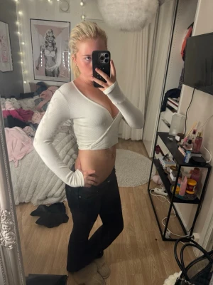 Vit croppad omlottopp - Säljer en vit croppad omlottopp med lång ärm och v-ringad hals. Toppen är ribbad och sitter tight, perfekt för dig som gillar en enkel men snygg stil. Passar till både jeans och kjol.