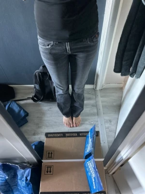 Grå bootcut jeans med broderi - Snygga grå bootcut jeans med slitningar och broderade detaljer på bakfickorna. Jeansen har klassisk femficksdesign, knappgylf och kontrastsömmar. Perfekta för dig som gillar en avslappnad men trendig stil.