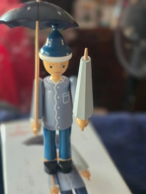 Kay Bojesen Ole luk øje  - Unik kay bojesen Ole luk öje träfigur i blått och vitt med en stjärnmönstrad svart paraply och blå mössa. Figurerad ansikte med målade detaljer, blå jacka med vita knappar och ficka, samt blå byxor och svarta skor. Perfekt som dekoration eller samlarobjekt.ny med låda köpt hos kids-world .se pris 1307.85 kr