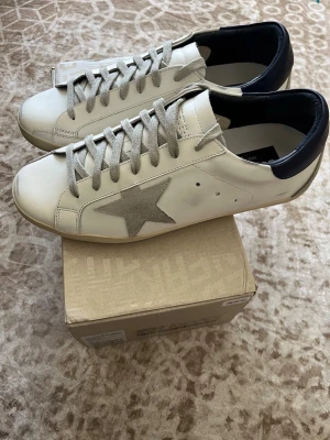 Golden Goose superstar - Säljer ett par Golden Goose Superstar i mycket fint skick. Skorna är väl omhändertagna och har den klassiska designen med den ikoniska slitna looken som modellen är känd för. Originalkartong medföljer.  • Mycket bra skick • Originalkartong ingår • Rena och redo att användas