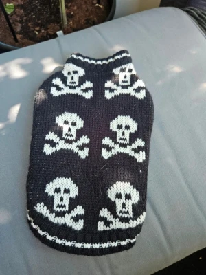 Stickad hundtröja med dödskallar - Säljer en svart stickad hundtröja med vita dödskallemotiv. Tröjan har hål för frambenen och är stretchig för att passa olika små hundar. Perfekt för att ge din hund en cool look under kyliga dagar.