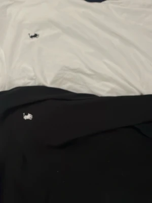 Tre klassiska t-shirts med logga - Säljer tre stilrena t-shirts, en vit en svart och en blå, båda med en liten broderad logga på bröstet. Perfekta basplagg med normal passform och korta ärmar. Passar till allt och är gjorda i mjuk bomull.
