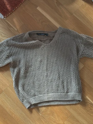 Beige stickad tröja med v-ringning - Säljer en beige stickad tröja med v-ringning. Tröjan har ett grovt ihåligt stickat mönster och ribbade muddar vid ärmslut och nederkant. Perfekt för lager på lager och enkel att styla till olika outfits. Sygg som överdragströja till bland annat fester.