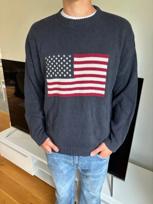Mörkblå stickad usa tröja - Hej 👋 denna tröja är en extremt lik variant på den otroligt populära Ralph lauren tröjan med USA flaggan‼️ modellen är 190 cm. Det är dock inte Ralph lauren som är märket‼️skriv vid funderingar