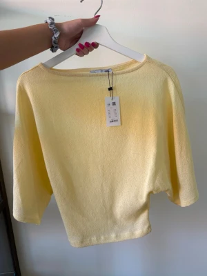 Gul poncho topp - Säljer en gul topp med rund halsringning. Toppen är tightare i midjan och har vida armar. 