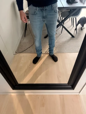 Nudie jeans Ljusblåa - Säljer ett par ljusblå nudie jeans med klassisk femficksdesign och normalhög midja. Jeansen har smal passform hela vägen ner. Perfekta för en avslappnad och trendig look.