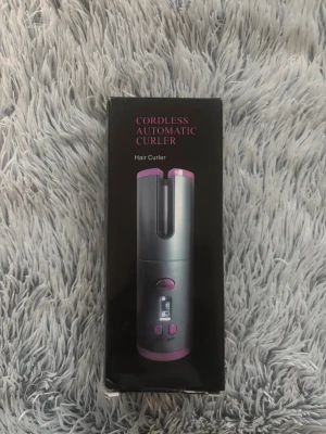 Sladdlös automatisk locktång - Säljer en sladdlös automatisk locktång i vitt med roségulddetaljer. Locktången har digital display och knappar för enkel användning. Perfekt för att snabbt fixa snygga lockar när du är på språng.