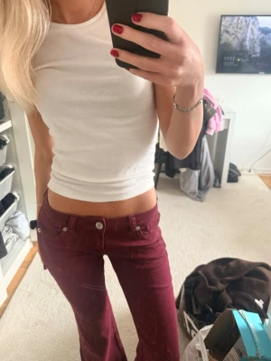 Vinröda bootcut jeans från H&M Divided - Säljer ett par vinröda bootcut jeans från H&M Divided. Jeansen är bootcut och aldrig använda