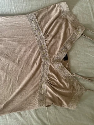Grönt linne med spets detaljer - Ett grönt spets linne med små glittrande detaljer
