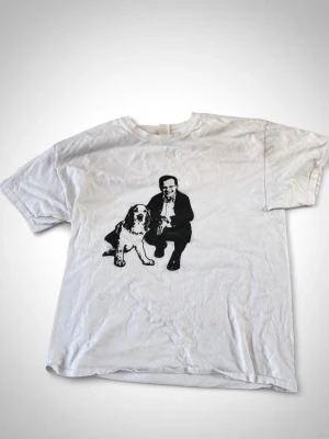Moderaterna tröja - Vit t-shirt i bomull med svart tryck framtill som föreställer Ulf Kristersson i kostym och en hund. Klassisk passform och rund hals. Perfekt för dig som gillar unika motiv och vill ha en enkel men cool look. Storlek L från början men är S eftersom jag krympte den