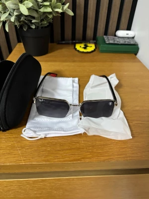 Ray-Ban solglasögon med silverbåge - Snygga Ray-Ban solglasögon med rektangulära, mörktonade glas och tunn silverfärgad metallbåge. Klassisk och stilren design som passar till många looks. Kommer med tillhörande fodral och putsduk.