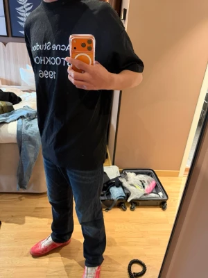 Svart Acne Studios t-shirt - Säljer en svart t-shirt från Acne Studios med tryck i vitt framtill där det står 'Acne Studios STOCKHOLM 1996'. T-shirten har normal passform och är kortärmad. Perfekt för dig som gillar stilrena och klassiska plagg.