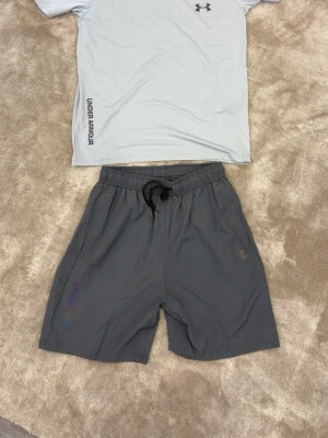 Under armour träningsset rainbow reflective -  Snyggt Under Armour träningsset med T-shirt och shorts. Rainbow-reflektiva detaljer som lyser upp snyggt i mörkret  Perfekt för träning, löpning eller vardagsbruk en. Storlek M men passar I även L.