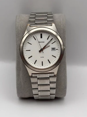 Klassisk silverfärgad klocka Moretime - Stilren klocka från Moretime med vit urtavla, datumvisning och silverfärgad länk i metall. Minimalistisk design med tydliga svarta markeringar och klassiskt armband i rostfritt stål. Perfekt accessoar för dig som gillar enkel och tidlös stil.