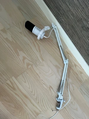 Vit mikrofonarm med fäste - Säljer en vit mikrofonarm i metall med fjädring och bordsfäste. Armen har justerbara leder och en kabel som löper längs armen. Perfekt för streaming, podd eller gaming setup.