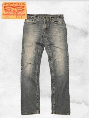 Levi's 511 grå tvättade jeans - Säljer ett par Levi's 511 jeans i grå tvättad denim med klassisk femficksmodell och raka ben. Jeansen har slitningar och en avslappnad look, perfekt för dig som gillar en casual look. Rikigt feta med en skön tvätt. 