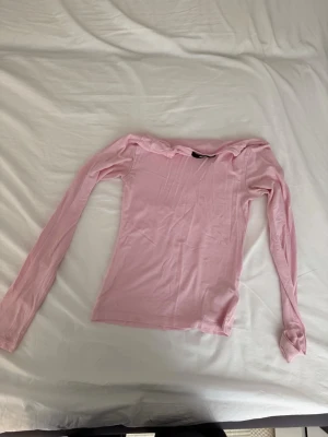Ljusrosa offshoulder topp BikBok - Söt ljusrosa offshoulder topp från BikBok i stretchigt material. Toppen har långa ärmar och en smickrande, figurnära passform som passar perfekt till jeans eller kjol. Enkel och stilren design som är lätt att matcha.
