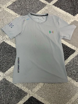 Under armour tröja - Säljer en ljusgrå tränings-t-shirt från Under Armour (HeatGear / Threadborne). Skönt och stretchigt material med "Fitted" passform.Sparsamt använd och i jättefint skick. Storlek M. Skickar snabbt!