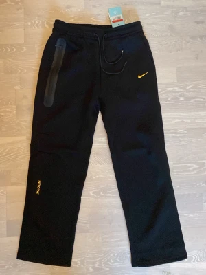 NOCTA x Nike Sweatpants - Tja! Säljer en par jättesnygg Svarta Nocta Nike byxor.                                                                       Storleken är Large och den har aldrig använts..                                                                             Det går även att få med hoodien också.                 Priset kan diskuteras och skickar inom 24 Tim 💨☺️