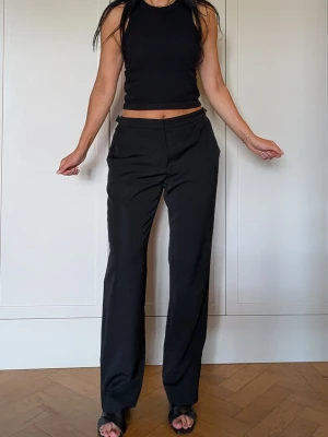Max Mara kostymbyxor i ny-ull - Svarta kostymbyxor med rak passform och hög midja, justerbar midja med spännen. 94% virgin wool, 6% elastan. Tidlösa och snygga byxor från Max Mara som gör just kostymer allra bäst, sparsamt använda, tunna och mjuka och sköna! 