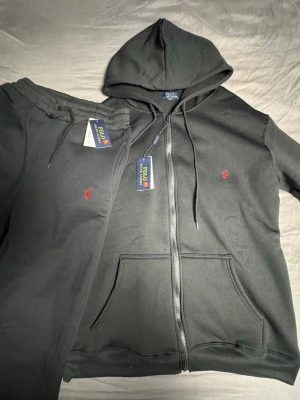 Ralph lauren set - Svarta mjukisbyxor från Polo Ralph Lauren med dragsko i midjan och broderad röd logga på benet. Tillverkade i mjukt material som känns skönt mot huden. Perfekta för en avslappnad och stilren look.