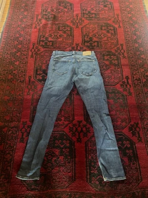 Blå slim fit jeans med raka ben - Säljer ett par klassiska blå jeans med slim fit och raka ben. Jeansen har fem fickor, normal midja och stängs med dragkedja och knapp. Passar perfekt till en avslappnad stil och är gjorda i ett mjukt denimtyg.