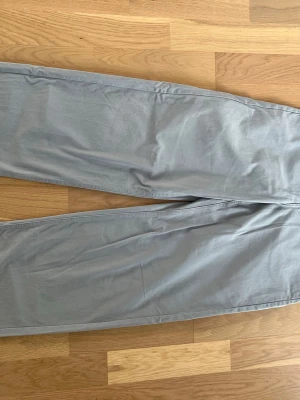 Ljusgrå chinos med raka ben - Snygga ljusgrå chinos med raka ben och klassisk passform. Byxorna har två bakfickor och är tillverkade i ett mjukt bomullsmaterial som ger en skön känsla. Perfekta för en avslappnad och stilren look.