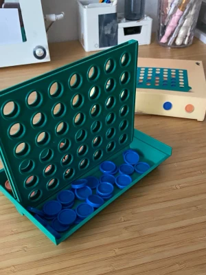 Fyra i rad spel med brickor - Säljer ett klassiskt Fyra i rad spel i grön plast med blå och röda spelbrickor. Spelet kommer med originalförpackning och är perfekt för två spelare. Lätt att ta med och enkelt att sätta upp på bordet. Kul för både familj och vänner!