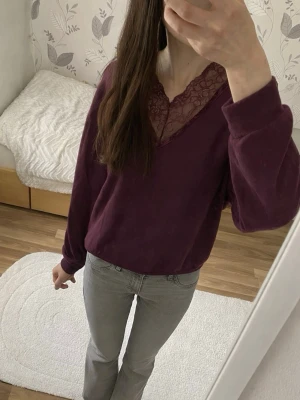 Vinröd topp  - Vinröd långärmad topp med v-ringning och dekorativ spets vid halsen. Modellen är croppad och har en avslappnad passform. 😊