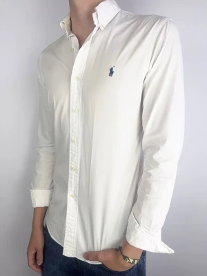 Ralph Lauren skjorta vit slimfit - Ralph Lauren Skjorta Märke: Polo Ralph Lauren Storlek: SPassform: Customfit Färg: Vit Skick: Mycket bra, möjligtvis superlite gulnad under armarna (syns knappt) Beskrivning: tunnare skjort material. Modellen på bilden: 183 cm / 72 kg