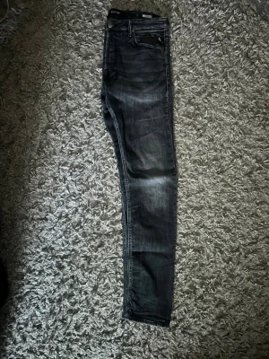 Mörkgrå skinny jeans från Replay - Snygga mörkgrå skinny jeans från Replay med klassisk femficksmodell och diskreta slitningar. Jeansen har smal passform och är tillverkade i stretchigt denimtyg för extra komfort. Perfekta för dig som gillar en stilren och modern look.
