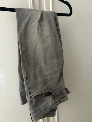 Grå low-bootcut jeans från 157 - Säljer ett par gråa bootcut jeans med låg midja från lager 157, Jeansen har en lätt utsvängd passform nedtill och är tillverkade i mjukt denimtyg. 