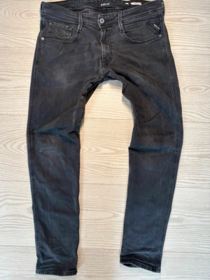 Svarta Replay slim fit jeans - Snygga svarta slim fit jeans från Replay med klassisk femficksmodell och diskreta slitningar. Jeansen har dragkedjegylf och detaljerade bakfickor med Replay-logga. Perfekta för en trendig och avslappnad stil 🙌Normalpris 1800+