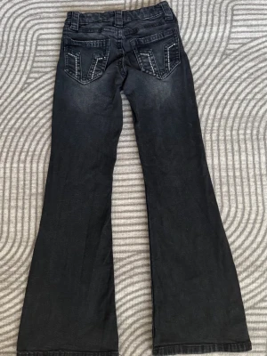 Svarta bootcut Gina tricot jeans - Snygga svarta bootcut jeans med coola detaljer på bakfickorna. Jeansen har klassisk femficksmodell, knappgylf och lätt utsvängda ben. Perfekta för dig som vill ha en avslappnad men trendig look.