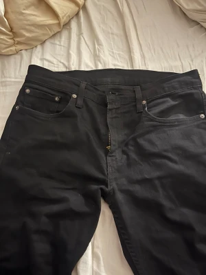 Svarta Levi's 502 jeans W32 L34 - Säljer ett par svarta Levi's 502 jeans med klassisk femficksdesign och dragkedjegylf. Jeansen har raka ben och är tillverkade i ett slitstarkt bomullsmaterial. Perfekta för dig som gillar en tidlös och clean look.