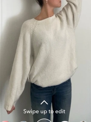Vit oversized stickad tröja - Mysig vit stickad tröja med oversized passform och långa ärmar. Tröjan har en enkel design med rund halsringning och är stickad i ett mjukt material som passar perfekt till jeans. Perfekt för kalla dagar när du vill vara både bekväm och snygg.