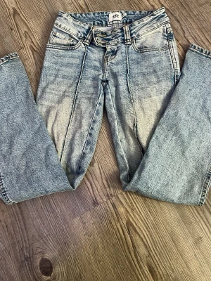 Ljusblå raka jeans med sömdetaljer - Säljer ett par ljusblå jeans med raka ben och markerade sömmar framtill. Jeansen har hög midja, dubbla knappar i linningen och klassiska fem fickor. Materialet är denim i bomull. Perfekta för en avslappnad och trendig look.