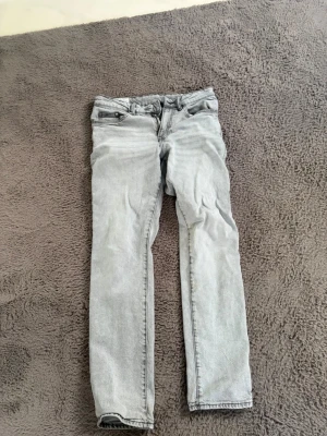 Ljusgrå straight jeans från H&M - Säljer ett par ljusgrå jeans från H&M i straight regular fit-modell. Klassisk femficksdesign och raka ben. Perfekta till en avslappnad stil och passar till det mesta. Tillverkade i bomullsmix för skön känsla.