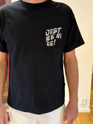 Svart t-shirt DrDenim stl M - Svart t-shirt med färgglatt tryck och texten 'JUST BE NICE' både fram och bak. 