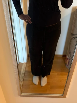 Svarta linnebyxor med dragsko - Svarta linnebyxor med avslappnad passform och dragsko i midjan. Perfekta för chill dagar hemma eller när du vill vara bekväm. Byxorna har raka ben och är gjorda i ett mjukt material som känns skönt mot huden.