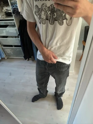 Svarta raka jeans herr med cool tvätt! - Säljer ett par svarta jeans med rak passform och klassisk femficksdesign. Jeansen har normal midja och är tillverkade i ett denimtyg som ger en avslappnad look. Perfekta till vardags för en stilren outfit.