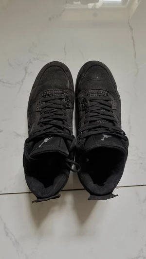 Svarta sneakers med meshdetaljer - Snygga helsvarta sneakers med meshdetaljer på sidorna och plösen. Skorna har en hög siluett, tjock sula och klassisk snörning. Materialet ser ut att vara en mix av mocka och textil. Perfekta för dig som gillar stilrena och sportiga skor.