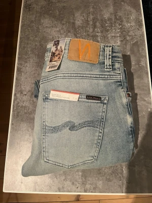 Nudie Grim Tim - Säljer ett par ljusblå jeans från Nudie Jeans med klassisk femficksmodell. De är modellen Grim Tim och de är endast använda en gång, säljer då de var lite små. Storlek 32/32