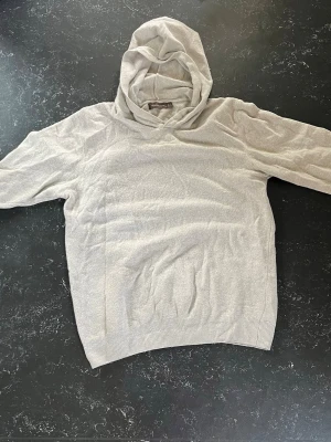 Ljusgrå kashmirhoodie från Oscar Jacobson - Säljer en stilren ljusgrå hoodie från Oscar Jacobson. Hoodien är tillverkad i mjuk ull och har en klassisk huva samt ribbade muddar vid ärmslut och nederkant. Perfekt för dig som gillar en clean och enkel look.