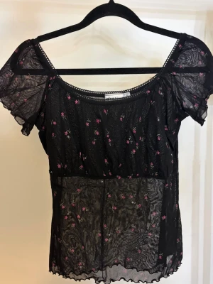 Svart blommig topp - En svart blus/topp med blommor på från Gina Tricot, storlek M.