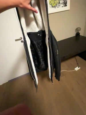 Svart pufferjacka med huva - Säljer en svart jacka  med huva och dragkedja. Jackan har ett quiltat foder och mjuk, vit teddy på insidan av kroppen och huvan. Perfekt för kalla vinterdagar och har en modern, avslappnad look. Passar längd 167 165 pris kan diskuteras vid snabb affär 