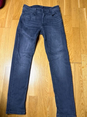 slim fit jeans Jack & Jones - Snygga mörkblå slim fit jeans från Jack & Jones med klassisk femficksmodell och stretchigt material för extra komfort. Jeansen har normal midja och smala ben, perfekta till en avslappnad stil. Passar dig som gillar en modern look.