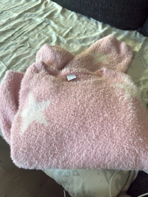 Rosa fluffig stickad tröja Lindex - Supermjuk och fluffig rosa stickad tröja från Lindex med vita stjärnor som detaljer. Storlek 170, men känns ganska stor i storleken, skulle passa dom som har storlek 160🥰