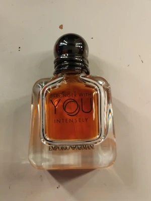 Emporio Armani Stronger With You Intensely - Emporio Armani Stronger With You Intensely är en parfym i en stilren, fyrkantig glasflaska med rundad svart kork. Doften har en varm bärnstensfärgad vätska och flaskan har tydlig logga och text på framsidan. Perfekt för dig som gillar exklusiva och intensiva dofter.