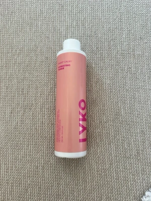 LYKO Deep Calm Hydrating Toner - Fräsch toner från LYKO i en cylinderformad plastflaska med rosa etikett och vit kork. Produkten heter Deep Calm Hydrating Toner och är återfuktande, perfekt för att balansera huden efter rengöring. Enkel att använda och snygg att ha i badrumshyllan.oöppnad och oanvänd 